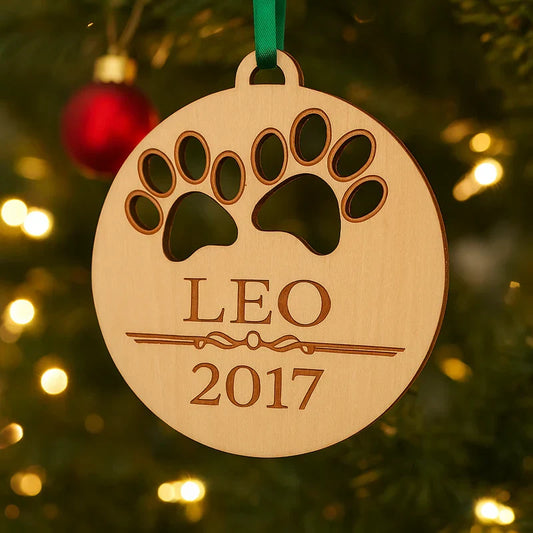 Personalized wood dog ornament engraved with the name Leo and the year 2017, hanging from a green ribbon on a lit Christmas tree branch