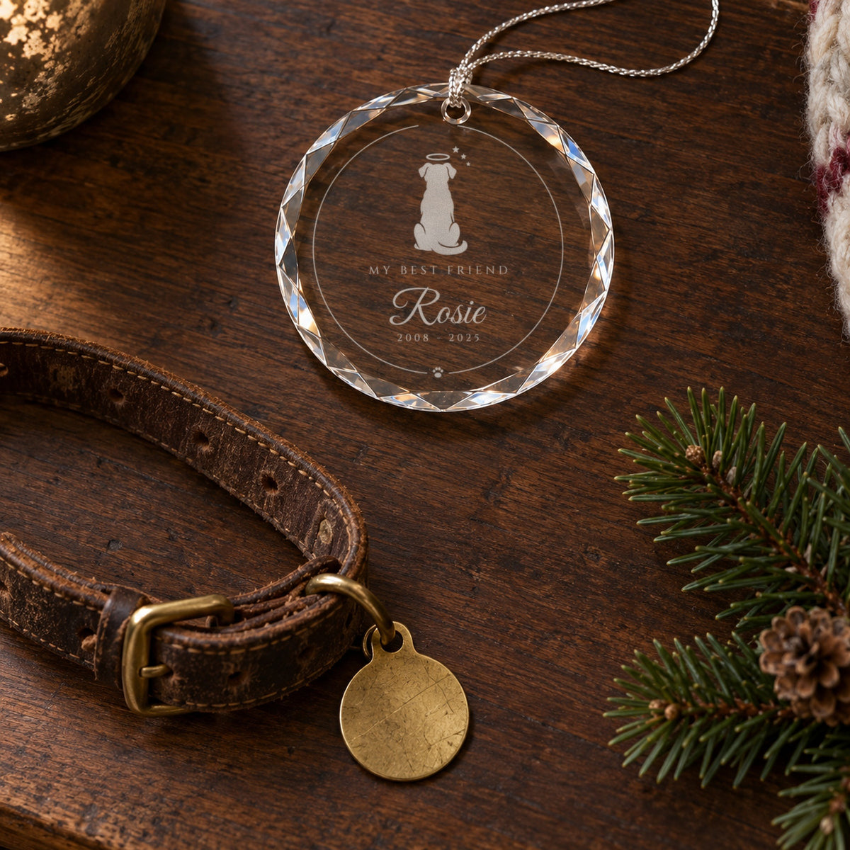 The engraved dog memorial ornament lying beside an old leather collar and a pine sprig on a walnut table, reading My Best Friend, Rosie
