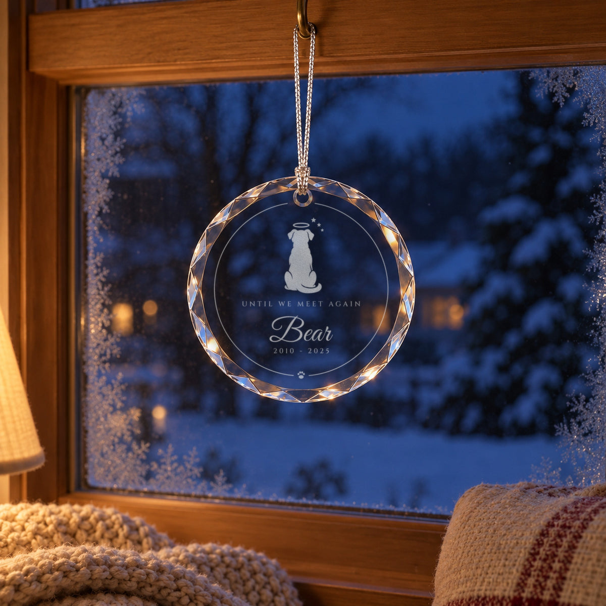 Dog memorial Christmas ornament hanging in a snowy window above a cozy window seat, engraved with a dog and a halo, Bear