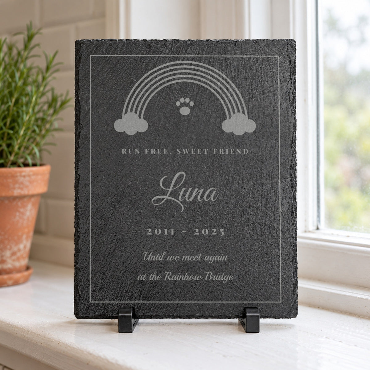 Rainbow Bridge Pet Memorial Slate engraved with a rainbow and paw print, Run Free, Sweet Friend, Luna and 2011 - 2025 on a white kitchen windowsill